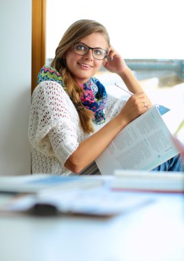 Yığın kitap ile oturan mutlu öğrenci kız