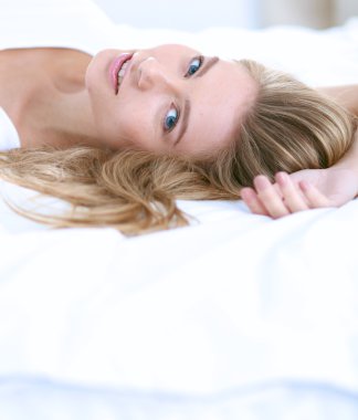 Güzel bir kadın yatağında uzanıyor.