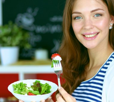 Salata yemek ve karışık salata tutan genç kadın
