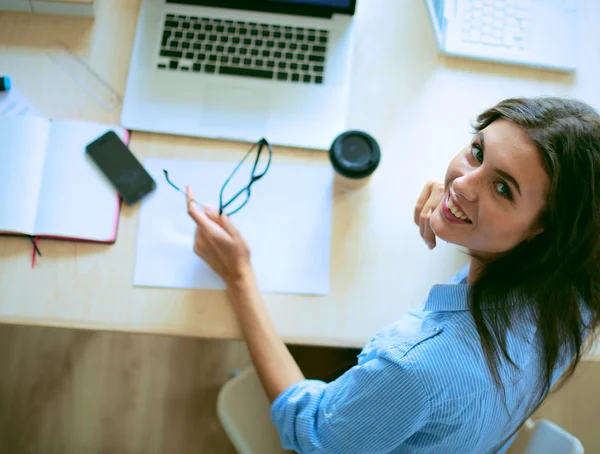 Jonge vrouw zit aan kantoor tafel met laptop — Stockfoto
