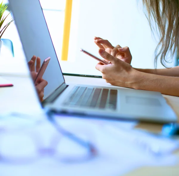 Jeune femme assise au bureau avec instruments, plan et ordinateur portable — Photo