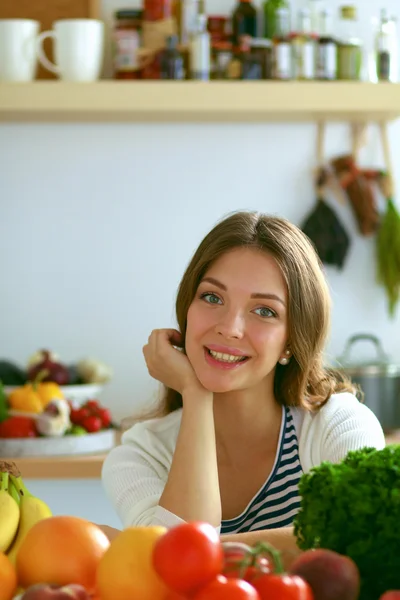 Jonge vrouw zit in de buurt van bureau in de keuken — Stockfoto