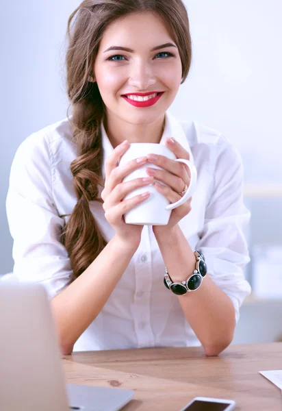 Jeune femme d'affaires assise sur le bureau avec une tasse — Photo