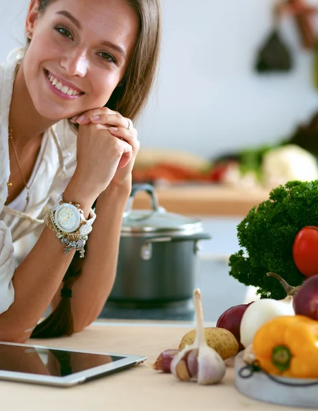 Mujer joven usando una tableta para cocinar en su cocina . — Foto de Stock