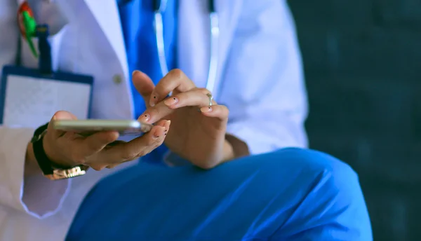 Junge Ärztin sitzt mit dem Handy — Stockfoto