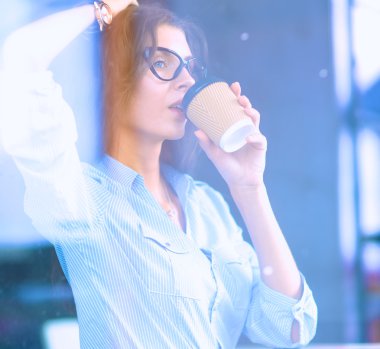 İş kadını ofiste dizüstü bilgisayarda çalışırken kupa içme