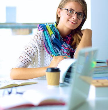 Kitapların arasında masa başında oturan genç bir kadın.