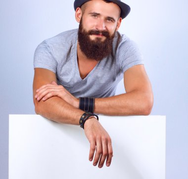 Şapkalı genç bir adamın portresi, beyaz arka planda, boş duruyor.