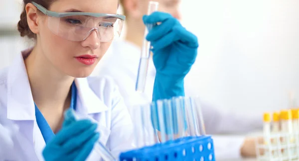 Woman researcher is surrounded by medical vials and flasks, isolated on white background — Stock Photo, Image