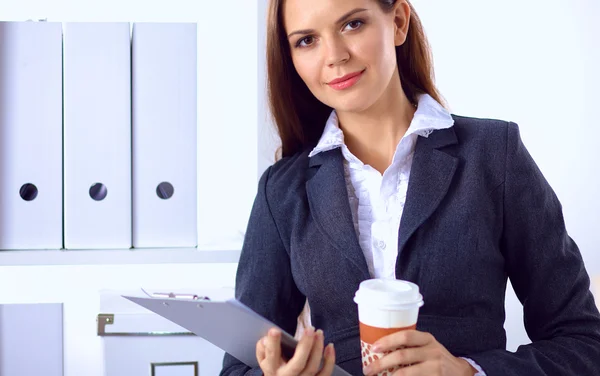 Atractiva joven empresaria de pie cerca del escritorio con carpeta en la oficina — Foto de Stock