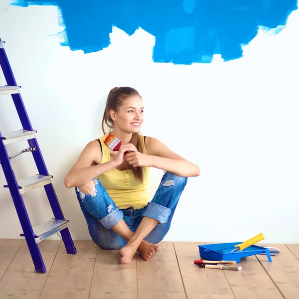 Portrét ženy malíře sedí na podlaze blízko zdi po malování. — Stock fotografie