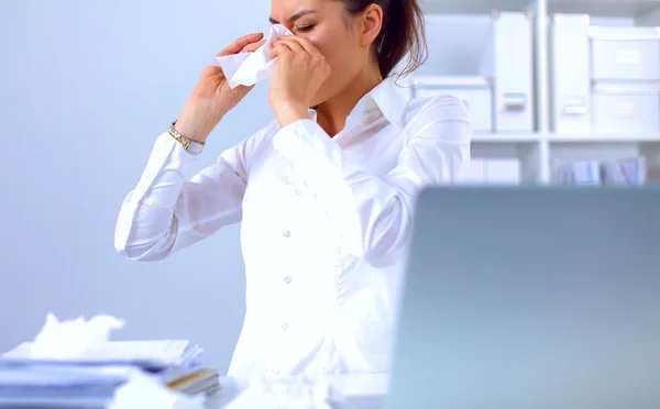 Junge Geschäftsfrau pustet sich die Nase, sitzt am Schreibtisch — Stockfoto