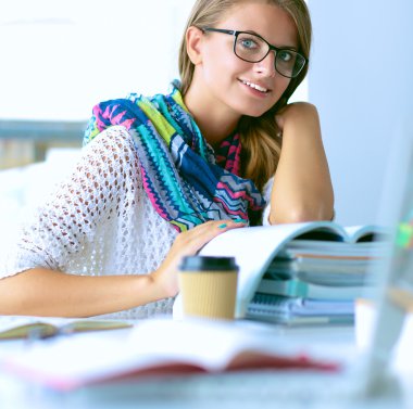 Kitapların arasında masa başında oturan genç bir kadın.