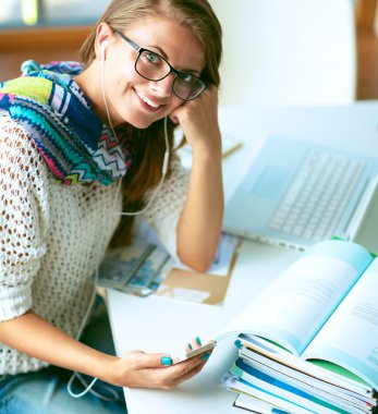 Kitapların arasında masa başında oturan genç bir kadın.