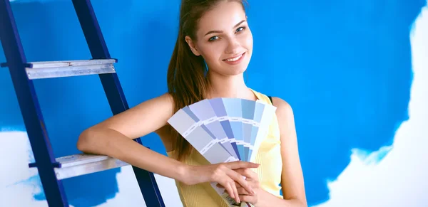 Ung vacker kvinna som håller färg palett, står nära väggen. — Stockfoto