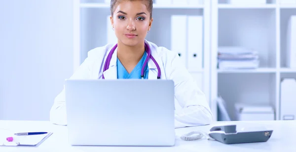 Female doctor sitting on the desk and working a laptop in hospital — Stock Photo, Image