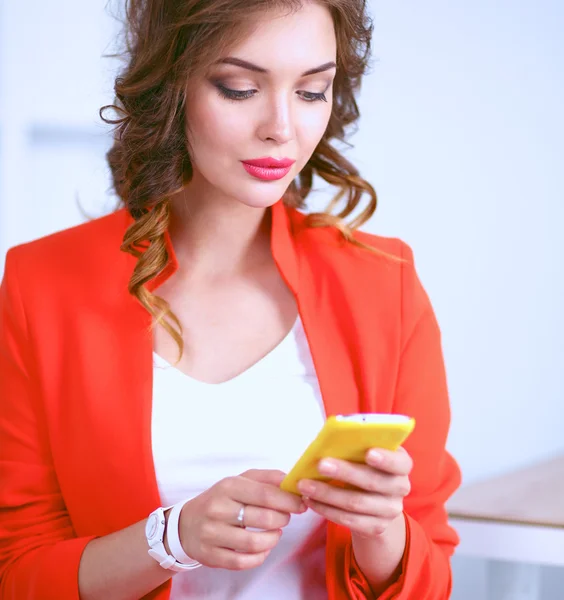Красивая деловая женщина, используя мобильный телефон стоя в офисе — стоковое фото