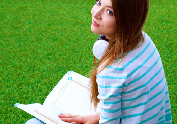 Vrouw lezing boek zit op het groene gras — Stockfoto