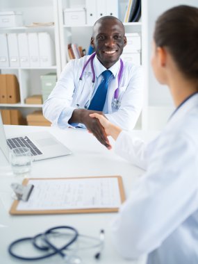 Ofiste tokalaşırken gülümseyen iki genç doktor.