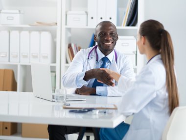 Ofiste tokalaşırken gülümseyen iki genç doktor.