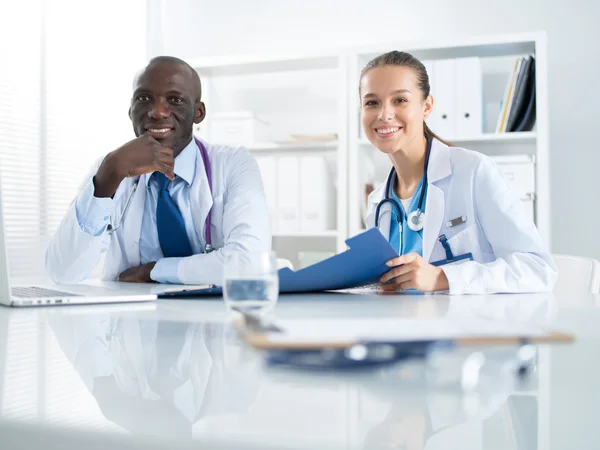 Dos doctores trabajando en una carpeta importante en un consultorio médico — Foto de Stock