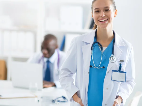Seorang dokter wanita tersenyum dengan folder di dalam ruangan yang seragam — Stok Foto