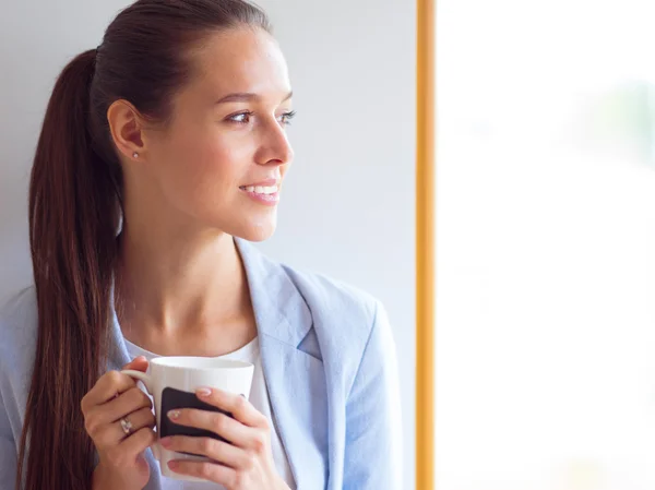 Aantrekkelijke vrouw achter balie in kantoor met afhaalmaaltijden koffie. — Stockfoto