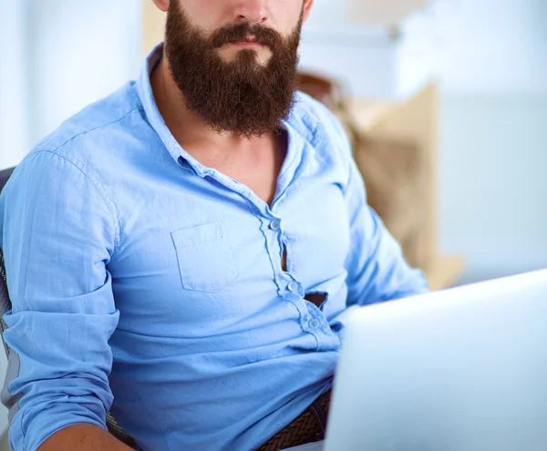 Guapo joven sentado y trabajando en el ordenador portátil —  Fotos de Stock