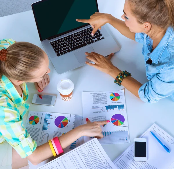 Due donne che lavorano insieme in ufficio, sedute sulla scrivania — Foto Stock