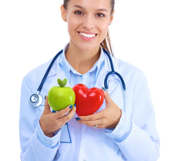 Beautiful smiling female doctor holding red heart and green apple — Stock Photo, Image