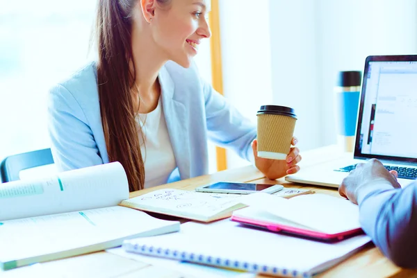 Attractive woman sitting at desk in office, working with laptop , having takeaway coffee. — Stock Photo, Image