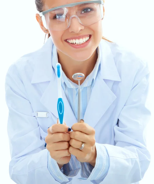 Bela dentista feminina segurando e mostrando uma escova de dentes isolada em um fundo branco — Fotografia de Stock