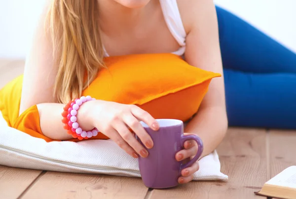 Smiling young woman lying on a white floor with pillow — Stock Photo, Image