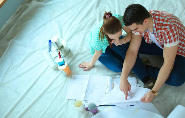 Pareja joven sentada en el suelo y calculando sobre sus ahorros — Foto de Stock