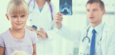 Kadın doktor ameliyatta steteskopla çocuğu muayene ediyor.