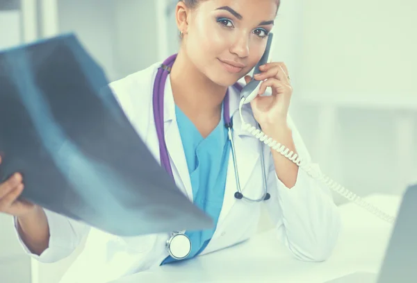 Jovem médica estudando radiografia sentada na mesa — Fotografia de Stock