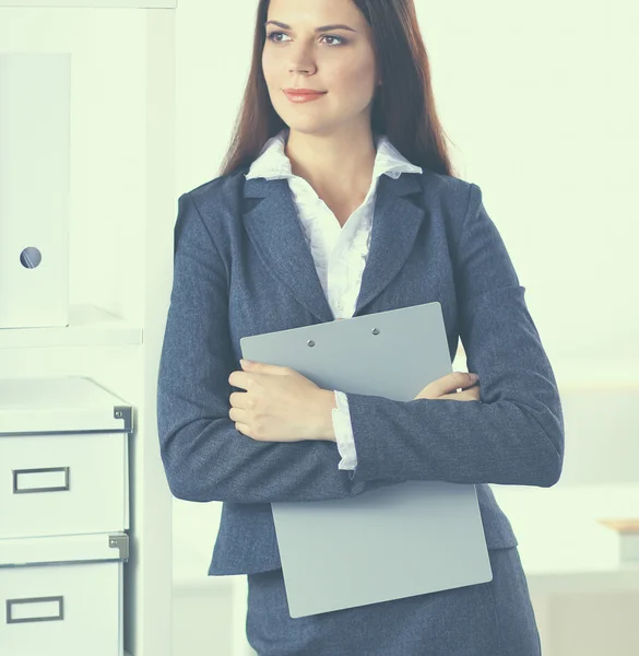 Привлекательная молодая деловая женщина, стоящая возле стола с папкой в офисе — стоковое фото