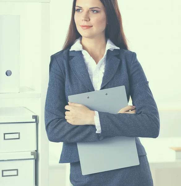 Attraktive junge Geschäftsfrau steht mit Ordner am Schreibtisch im Büro — Stockfoto