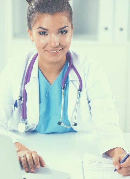 Female doctor sitting on the desk and working a laptop in hospital — Stock Photo, Image