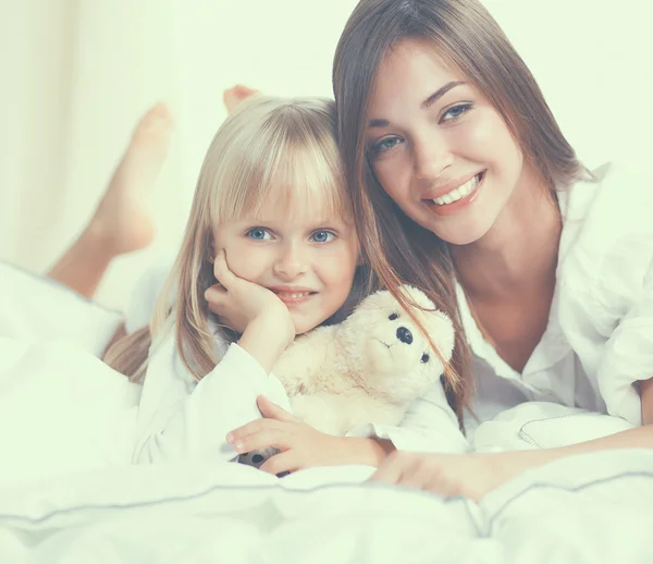 Woman and young girl lying in bed smiling — Stock Photo, Image