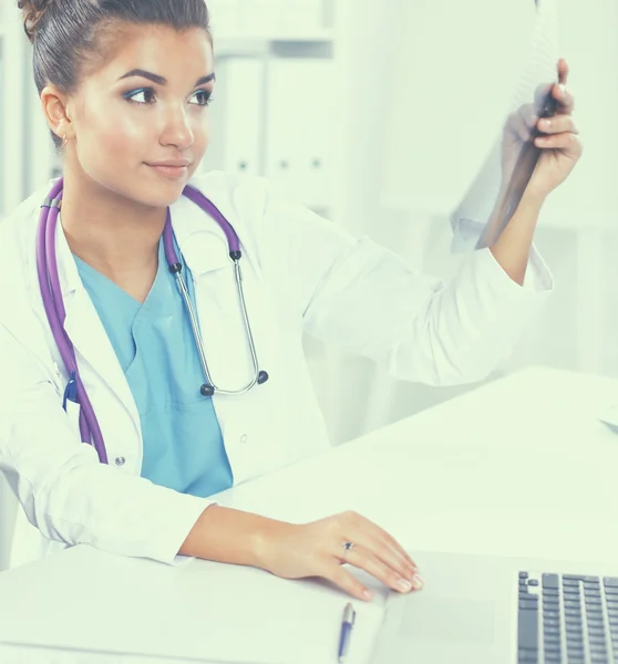 Ung kvinnlig läkare studerar röntgenbild sitter på skrivbordet — Stockfoto