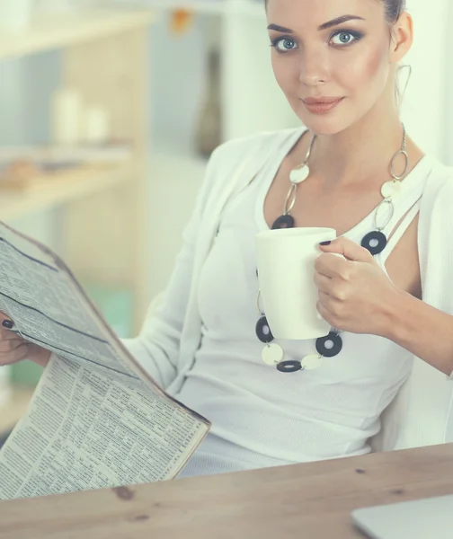 Cute businesswoman holding newspaper sitting at her desk in office — Stock Photo, Image