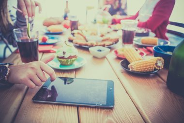 Bir grup insan ahşap masada otururken birlikte yemek yiyorlar.