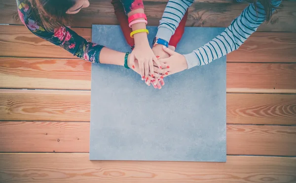 Persone con la mano accatastati seduti sulla scrivania — Foto Stock