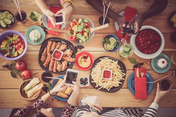 Gruppo di persone che cenano insieme seduti a un tavolo di legno — Foto Stock