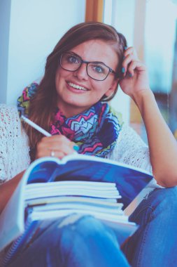 Kitapların arasında masa başında oturan genç bir kadın.