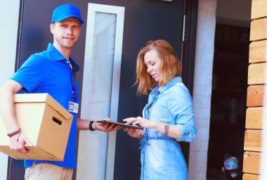 Mavi üniformalı gülümseyen kurye servis konseptine paket kutusu teslim eden teslimatçı. Mavi üniformalı gülümseyen teslimatçı.