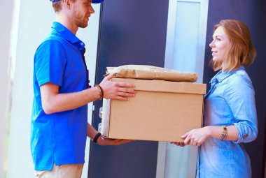 Mavi üniformalı gülümseyen kurye servis konseptine paket kutusu teslim eden teslimatçı. Mavi üniformalı gülümseyen teslimatçı.