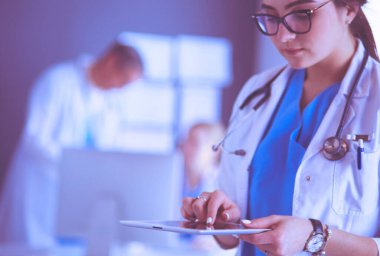 Hastane lobisinde tablet bilgisayar kullanan kadın doktor.