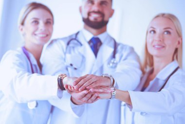 Doktorlar ve hemşireler tıbbi bir ekipte el ele tutuşuyorlar.